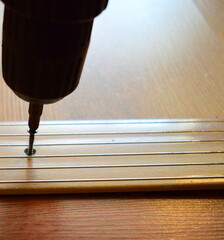Fixing the threshold with an electric screwdriver. Repair of residential premises.