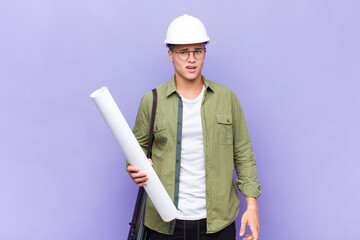 young blonde man feeling puzzled and confused, with a dumb, stunned expression looking at something...