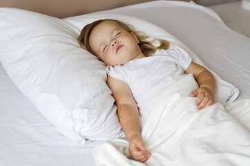 Blonde sweetest  toddler girl sleeping peacefully in white bed. Daytime sleep of the child. Bedtime