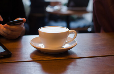 White cup of coffee on table in cafe