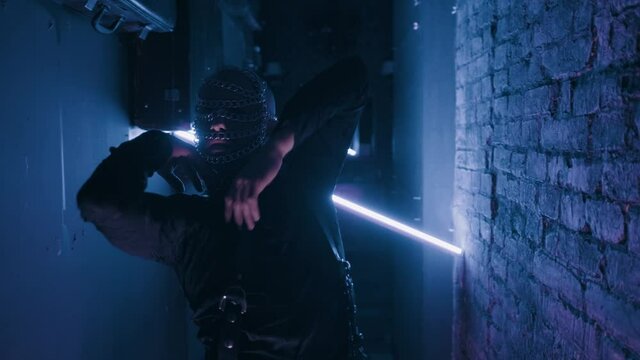Sexy dancer man in the chain mask on the dark night club background. Filmed in fluorescent clothing under UV black light. Club party glamor style. Creative art