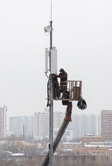 Technicians install mobile signal amplification devices on tower. It's nasty. Unrecognizable people. Technology concept, 5G, equipment improvement, professions, microwave danger, internet of things