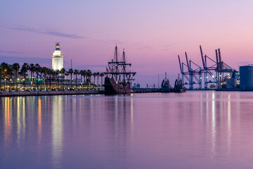 Black Pirate Ship in Malaga Port with Vivid Sunset Colors and Lighthouse