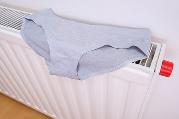 Drying wet underpants on radiator of central heating, casual ladies underwear hanging on a heater,...