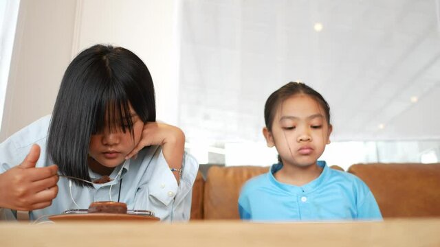 Young Asian and sister play mobile phone in living room
