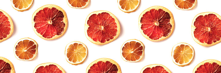 Pattern of dried slices of citrus on white background. Abstract food backdrop. Top view, flat lay style. Banner for website.