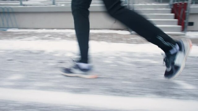 The runner's feet move along a snowy road. A planned run on a snowy day. Aerobic training that increases a person's endurance threshold.