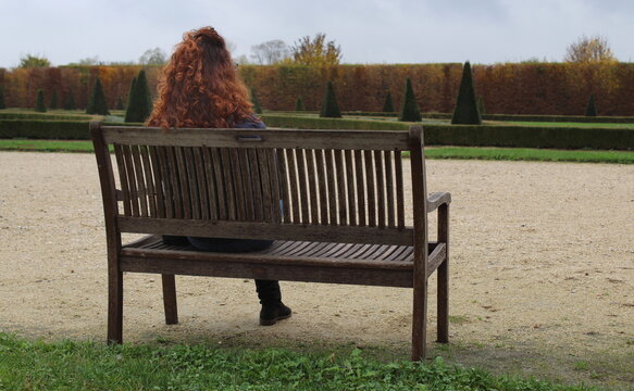 Ragazza dai capelli ricci seduta su una panchina nel parco in autunno