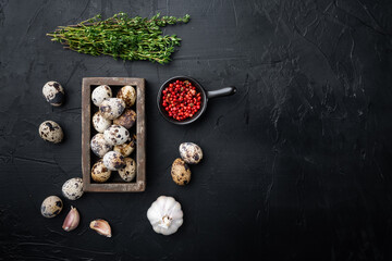 Fresh quail eggs, flat lay, on black textured background  with space for text