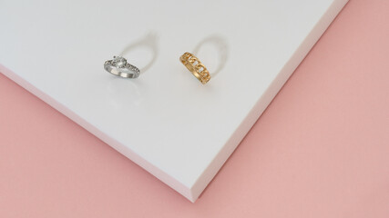 Precious golden rings with diamonds on white and pink background