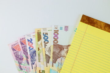 Yellow notebook write in the Ukrainian money grivna banknotes with white background