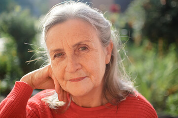 Portrait of a mature woman with grey hair spending time outdoors during sunny day, happy retirement