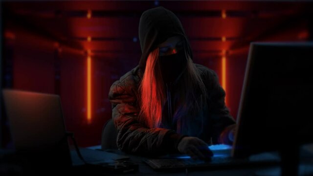 Young anonymous hacker woman with mask. Thief is stealing data from computer or hacking system. Hands in gloves are typing on the keyboard. Theft of cryptocurrency and bitcoin