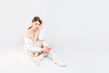 Girl all in white with red lips on an isolated white background. Girl posing in fashion style clothing. Difficult posing of the model.