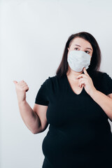 Woman in medical mask pointing thumb on copy space