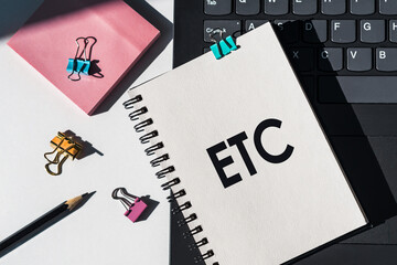 Notebook with tools and notes about ETC lies on laptop.