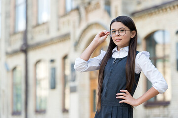 Little child in uniform with back to school look fix eyeglasses to correct sight, eyecare, copy space