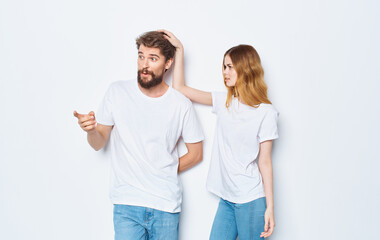 A guy and a beautiful woman in the same clothes on a light background are gesticulating with their hands 