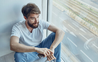 bearded man near window at home with phone internet technology interior