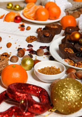 sweet food background for christmas or holiday decoration - chocolate candies, tangerines, nuts and dried fruits on white wood