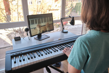 Boy learning to play the piano in distance learning via over the Internet - Powered by Adobe