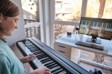 Homeschool European young boy learning piano from computer connecting to internet music online...