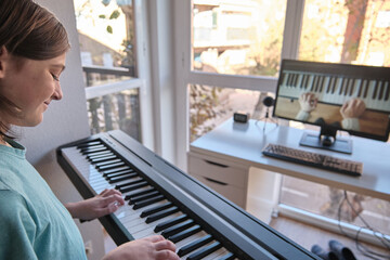 Homeschool European young boy learning piano from computer connecting to internet music online class by school teacher. New normal lifestyle and education, student study at home concept. © roberjzm
