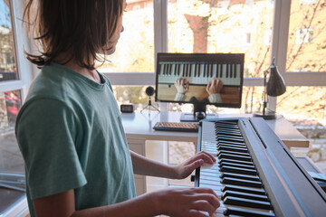Young boy having online piano class. Home education.