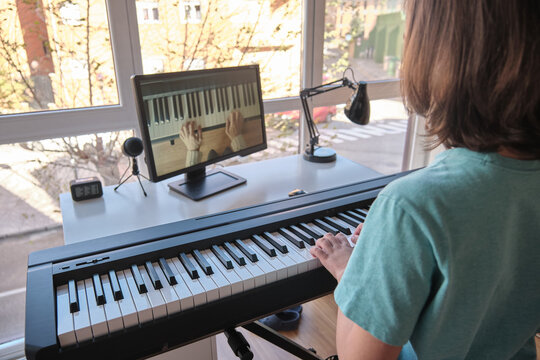 Boy learning to play the piano in distance learning via over the Internet