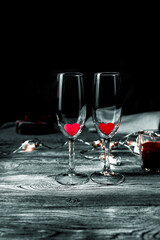Two glasses with red hearts inside on a black background. Concept of holiday backgrounds, February 14, love.