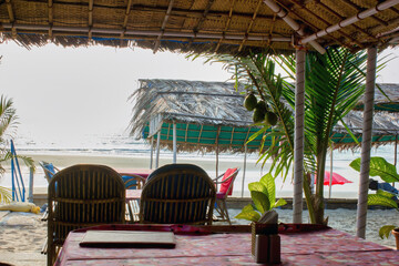 Fototapeta na wymiar A view from a customer in a restaurant located on a beach in Goa, India | Empty interior of a restaurant against arabian sea.