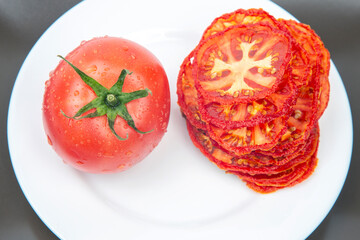 Fresh red tomato and dried tomato slices on a plate. Vitamin vegetable food