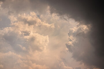 dark cloud framing large white cumulus clouds distant and illuminated by intense sunlight.