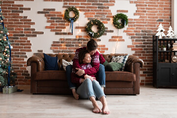 Obraz premium Husband and wife in identical knitted sweaters have fun together celebrating Christmas.