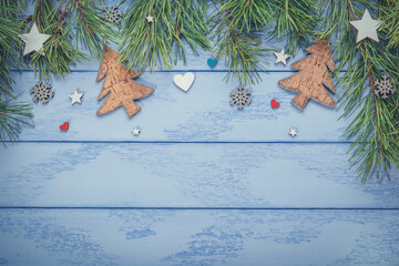 Christmas or New Year flat lay: pine branches with some wooden decorations on the blue boards