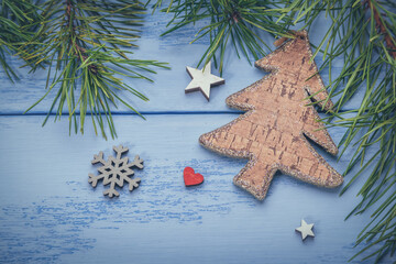 Pine branches, wooden Christmas tree and some decorations on the blue boards