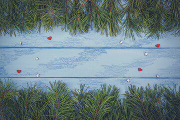 Christmas or New Year background: pine branches and small wooden hearts on the blue boards