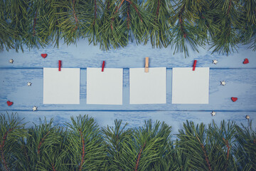 Christmas or New Year mock up: pine branches and four white stickers with little clothespins on the blue boards