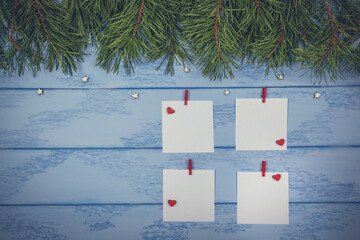 Christmas or New Year mock up: pine branches and white stickers with red clothespins and little wooden stars on the blue boards
