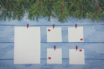 Christmas or New Year mock up: pine branches and white stickers with red clothespins, little wooden stars and hearts on the blue boards