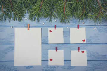 Christmas or New Year mock up: pine branches and white stickers with red clothespins and some wooden decorations on the blue boards