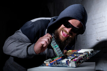 Bearded hacker in sunglasses and hoodie cracking the hardware