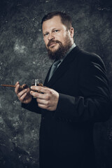 Solid confident bearded man in suit with glass of whisky and cigar