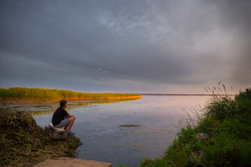 Teenboy sitting and relaxing on lake beach