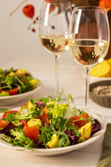 Light breakfast or dinner, mix salad with salmon and different seeds and two glasses of white wine, plate with salad and cornbread close up