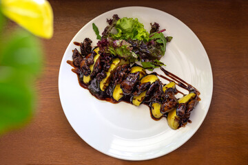 Caramelized duck liver with apples on a white plate, top view