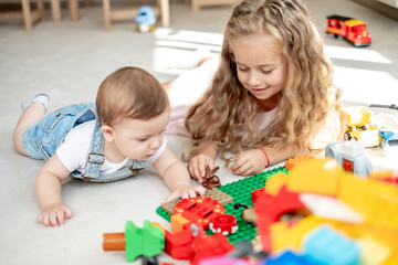 Fototapeta premium Brother and sister playing together, girl spending time with sibling, teaching him to explore life, cuties