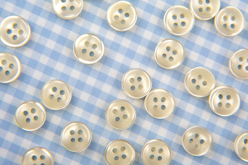 Plastic shiny buttons for clothes on a fabric background. Fashion and clothing. Factory industry