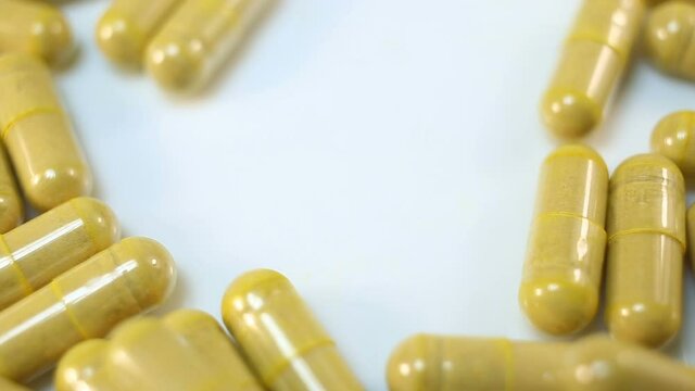 Transparent capsules with bright yellow powder of natural pigment extremely close-up, real time, medicine, pharmacy