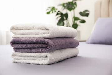 Fototapeta na wymiar Stack of clean towels on bed indoors